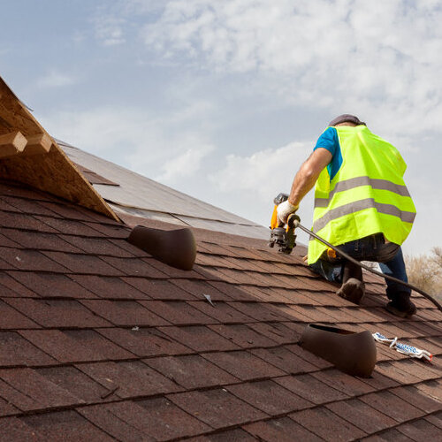 A Roofer Nails in Shingles